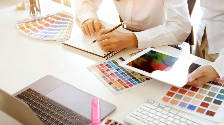 Two people looking at colour swatches for a graphic design project.